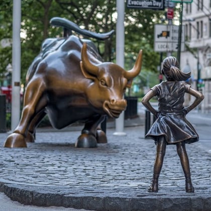 Charging bull statue on Wall Street facing statue of girl