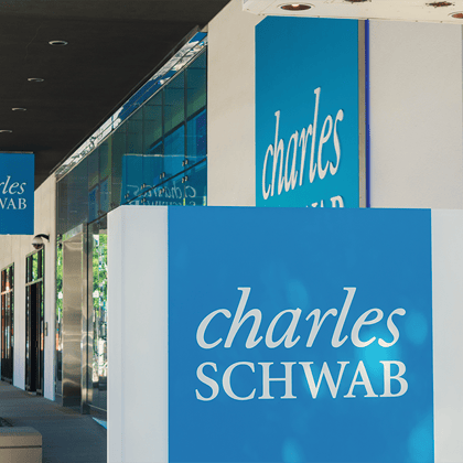 Several Charles Schwab blue and white corporate logos on large sign boards