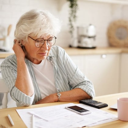 Image showing a female woman at or near age 65 looking at paperwork and a calculator