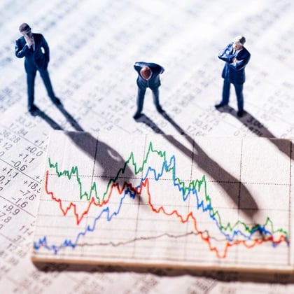 A stock image of three men looking down at a declining stock market, symbolized by 3 falling lines of green, blue and red.