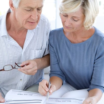 An older couple, signing papers. (Image: Shutterstock)