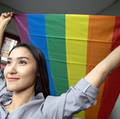 Asian LGBT woman holding LGBTQ rainbow flag, lesbian pride or LGBT pride movement, inclusivity, diversity of people concept