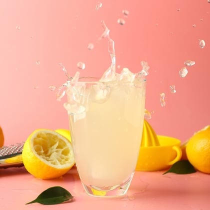 Glass of tasty cold lemonade with splashes on color background. Credit: Pixel-Shot/Adobe Stock