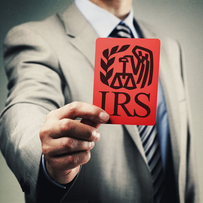 Man in suit holding card with IRS logo