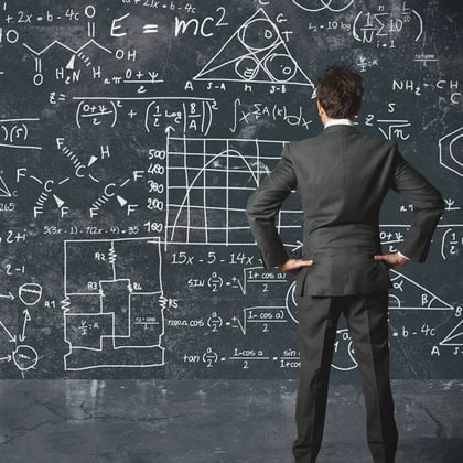 A businessman in a suit looking at a chalkboard of math