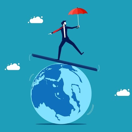 Businessman balancing on top of globe with umbrella