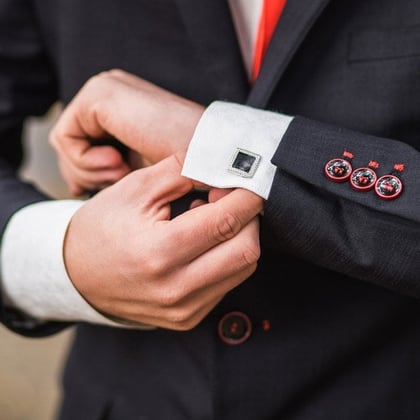 A man looking at his cufflinks while adjusting them