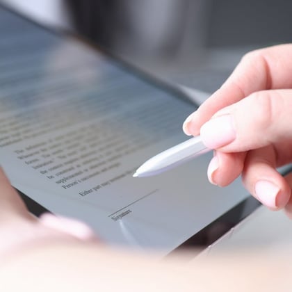 An individual using a stylus to sign a document on a tablet