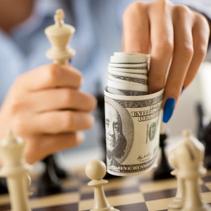 A man holding money and playing chess