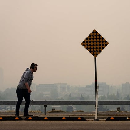 A skateboarder passes buildings shrouded in smoke from wildfires in Calgary, Alberta, Canada, on Wednesday, May 17, 2023. Scenes in Calgary were reminiscent of Seattle last summer and San Francisco in 2020 as wind currents blew smothering wildfire smoke into those population centers, compromising air quality. Photo: Todd Korol/Bloomberg