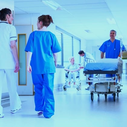 A nurse pushes a patient on a gurney through a hospital corridor