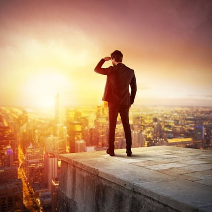 Businessman standing on edge of a building looking to the future