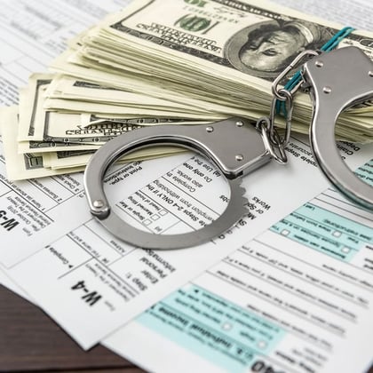 Handcuffs and money on top of tax forms