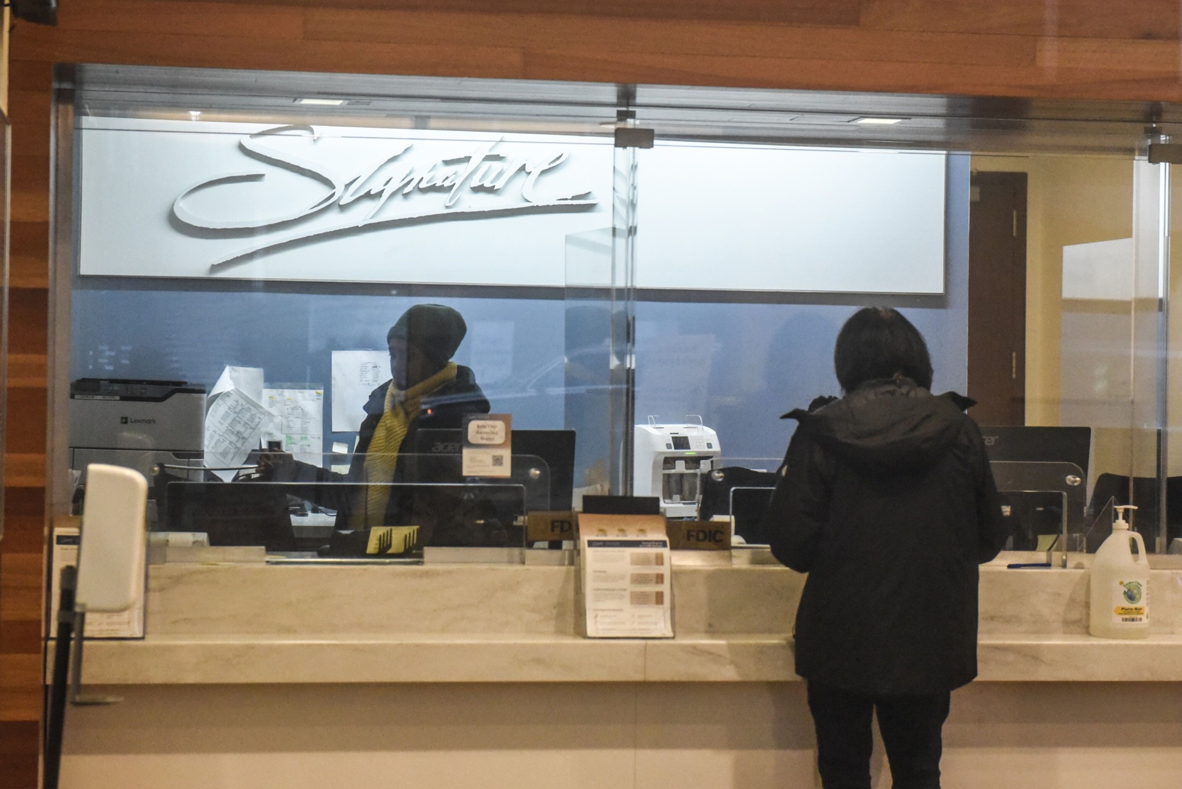 A worker assists a customer at a Signature Bank branch in New York.